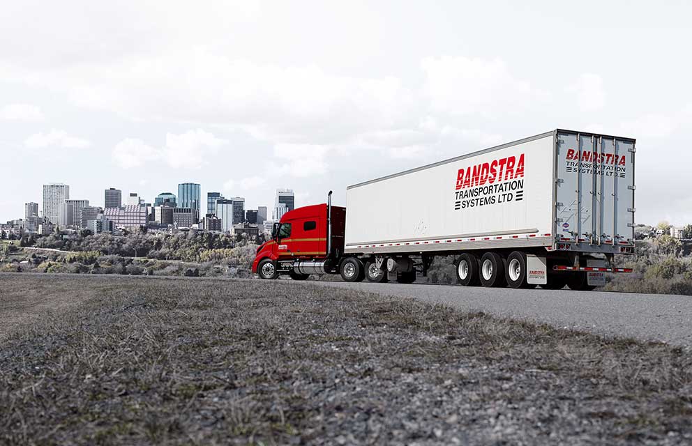 Bandstra highway truck driving in front of cityscape 