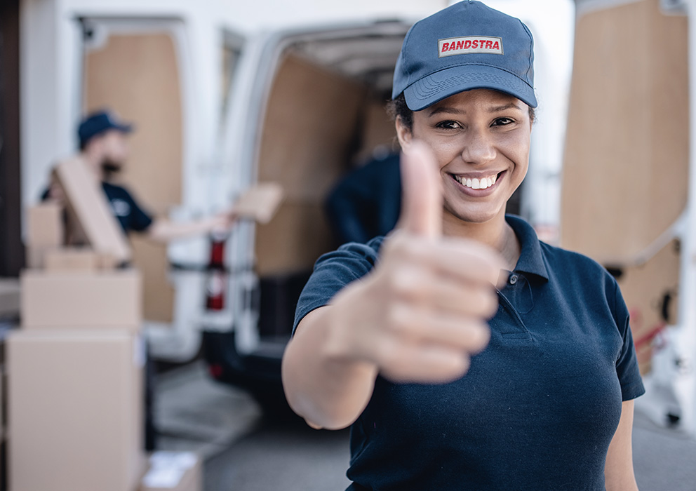 Bandstra team member giving thumbs up in front of company van being loaded with charity packages