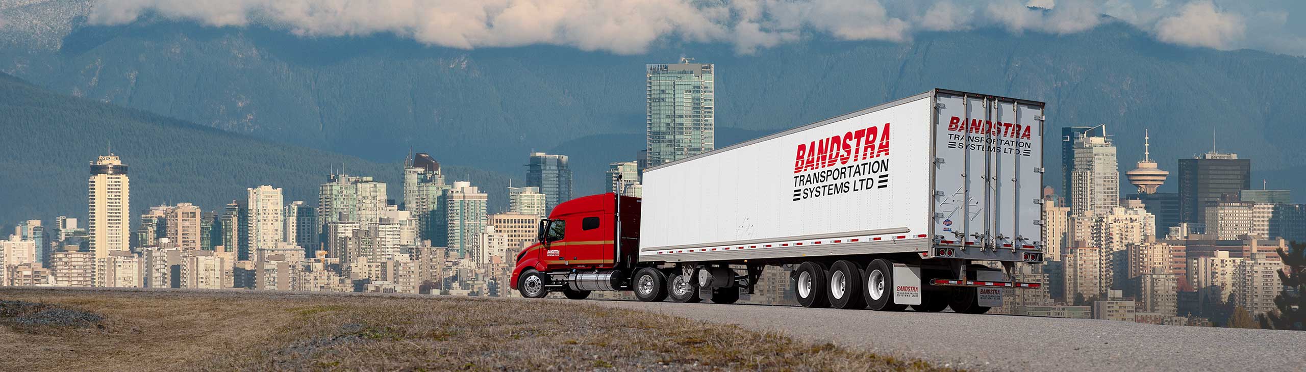 Bandstra tractor trailer driving toward British Columbia cityscape